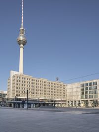 the television tower stands tall behind other buildings, in the city square of a large city