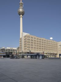 the television tower stands tall behind other buildings, in the city square of a large city