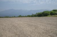 a field with mountains in the distance and hills in the distance in the foreground