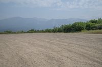 a field with mountains in the distance and hills in the distance in the foreground