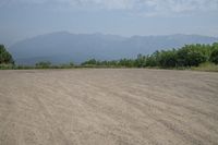 a field with mountains in the distance and hills in the distance in the foreground