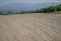 a field with mountains in the distance and hills in the distance in the foreground