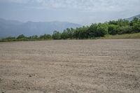 a field with mountains in the distance and hills in the distance in the foreground