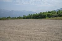 a field with mountains in the distance and hills in the distance in the foreground