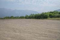 a field with mountains in the distance and hills in the distance in the foreground