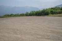 a field with mountains in the distance and hills in the distance in the foreground