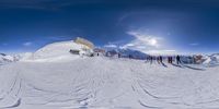 a snow covered mountain with skiers standing around it in the snow and looking at the sky