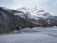 a mountain road with mountains and trees in the background in wintertime under cloudy skies