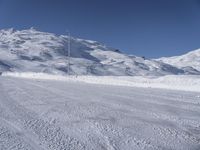 a lone man rides the snowboard on a track in front of a snowy mountain