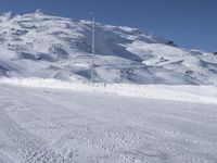 a lone man rides the snowboard on a track in front of a snowy mountain