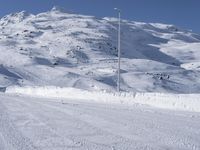 a lone man rides the snowboard on a track in front of a snowy mountain