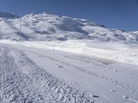 a lone man rides the snowboard on a track in front of a snowy mountain