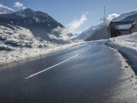 a road on the side of a mountain covered in snow and ice with buildings and power lines