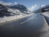 a road on the side of a mountain covered in snow and ice with buildings and power lines