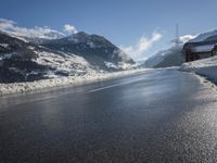 a road on the side of a mountain covered in snow and ice with buildings and power lines