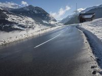 a road on the side of a mountain covered in snow and ice with buildings and power lines