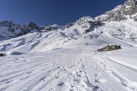 a snowboarder going down the side of a slope, toward some large snow mountains