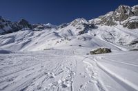 a snowboarder going down the side of a slope, toward some large snow mountains