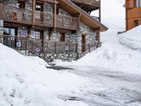 a ski lodge in the mountains of a village on top of a mountain, with snow piled to their ground and stairs