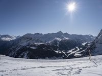 the mountains are covered in snow as people cross country ski by ski tracks through them