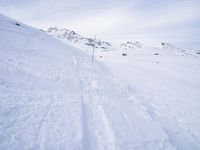 snow covered slope in the middle of a ski area as people ski on it near ski lift