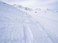 snow covered slope in the middle of a ski area as people ski on it near ski lift