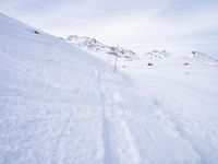 snow covered slope in the middle of a ski area as people ski on it near ski lift