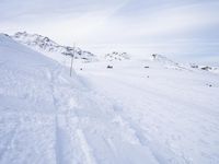 snow covered slope in the middle of a ski area as people ski on it near ski lift