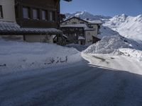 an empty snow covered road in front of a snow capped mountain range in the snow