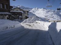 an empty snow covered road in front of a snow capped mountain range in the snow