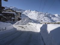 an empty snow covered road in front of a snow capped mountain range in the snow