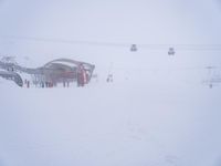 an image of a person skiing on the snow covered slopes near a ski lift and building