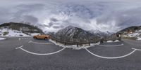 two cars in the road near a wooden fence with mountains in the background on cloudy day