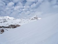 snowboarder on a ski slope near a town in the background of mountains and ski lift