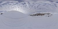 a person on skis and a camera in front of some snow covered mountains and clouds