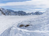 a mountain slope with snow piled up on the sides and behind a mound of snow with a hole