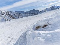 a mountain slope with snow piled up on the sides and behind a mound of snow with a hole