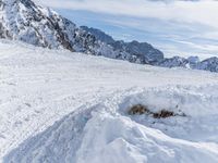 a mountain slope with snow piled up on the sides and behind a mound of snow with a hole