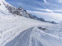 a mountain slope with snow piled up on the sides and behind a mound of snow with a hole