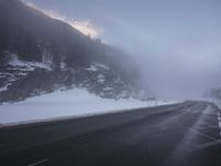 a snowy highway in the middle of winter time with a bench on the roadside side