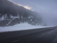a snowy highway in the middle of winter time with a bench on the roadside side