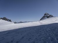 a person snow skiing down a snowy mountain side way on skis with mountains in the distance