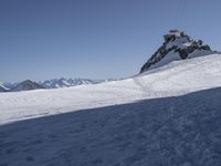 a person snow skiing down a snowy mountain side way on skis with mountains in the distance