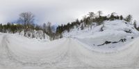 the snow is covering two roads as a car passes by at a stop light with trees in the background