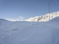 a snowy mountain has a ski slope in front of it and a sign indicating a ski area