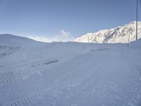 a snowy mountain has a ski slope in front of it and a sign indicating a ski area