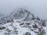 a mountain covered in snow with no people on it and rocks on it near a rocky peak