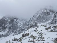 a mountain covered in snow with no people on it and rocks on it near a rocky peak