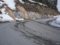 a steep cliff with a sloped off section on the side next to it, has snow piled around it
