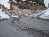 a steep cliff with a sloped off section on the side next to it, has snow piled around it